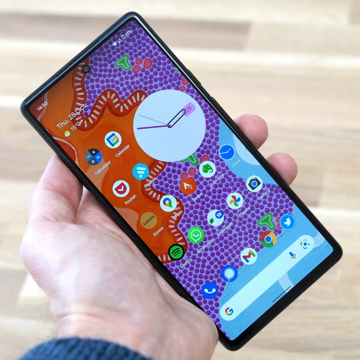 Smartphone displaying colorful app icons and a clock on the home screen.